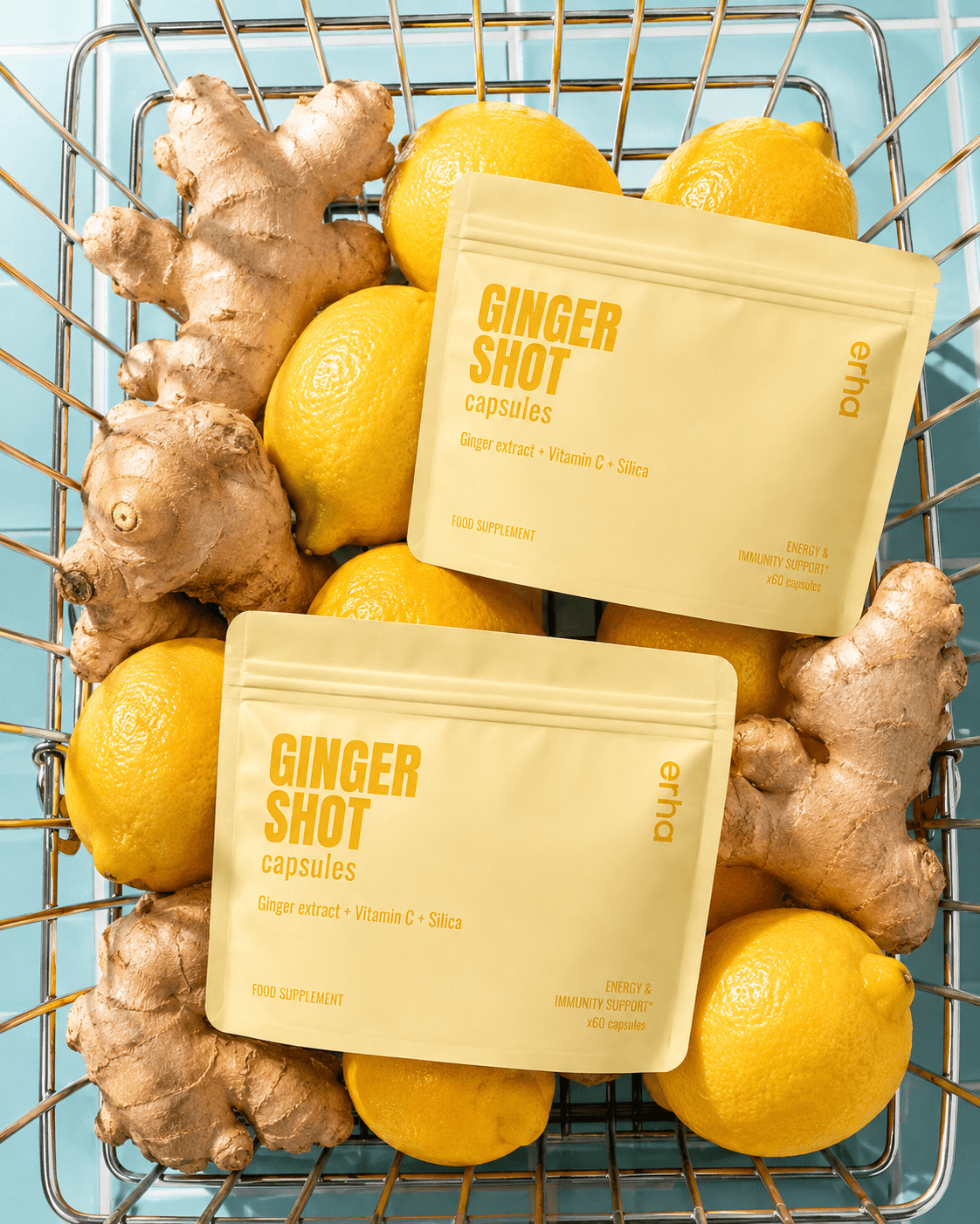 Erha Ginger Shot Capsules pouches arranged with ginger and lemons in a shopping basket