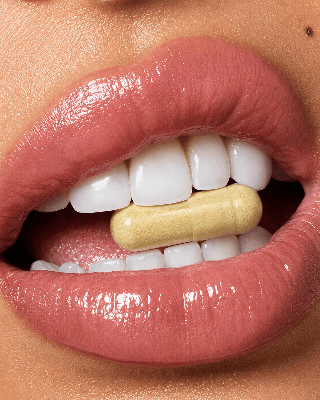 Close-up of lips holding a golden Ginger Shot capsule